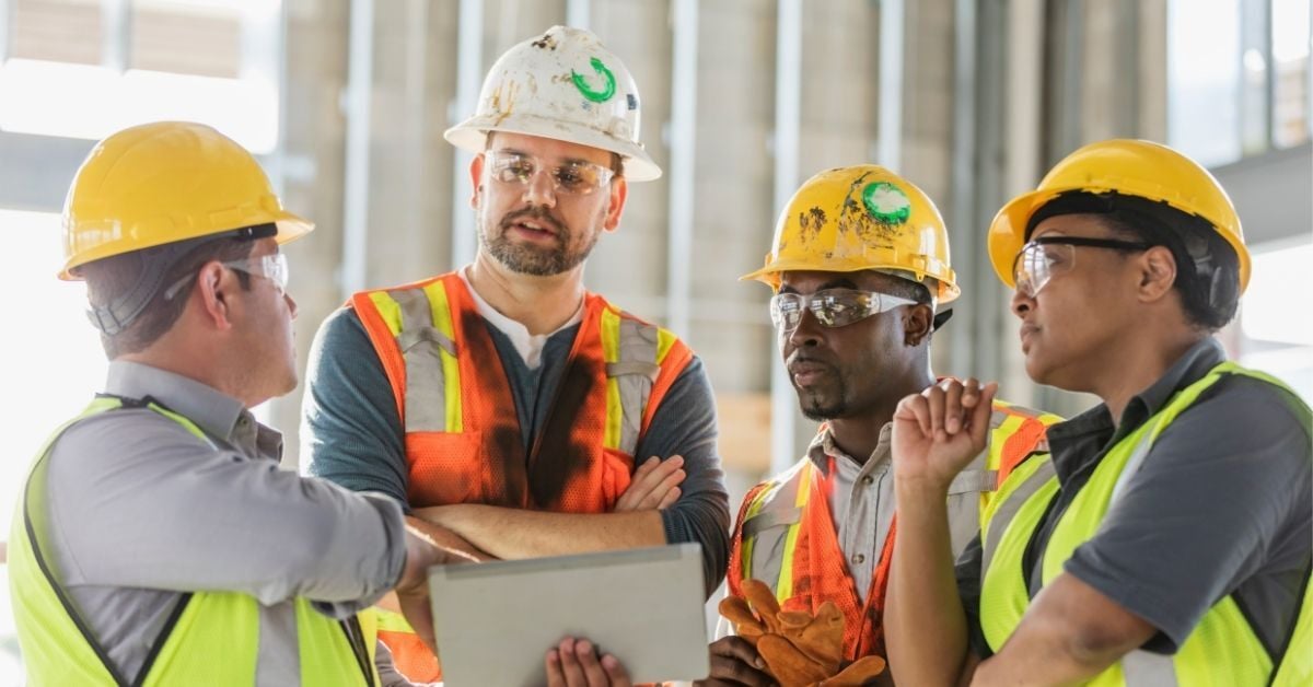 Trade hesitancy blog - a group of trade workers gathers for a meeting around an ipad photo