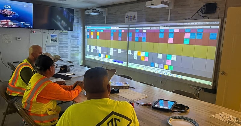 3 employees at PC Construction viewing their weekly schedule with Nialli Visual Planner in a meeting room. 
