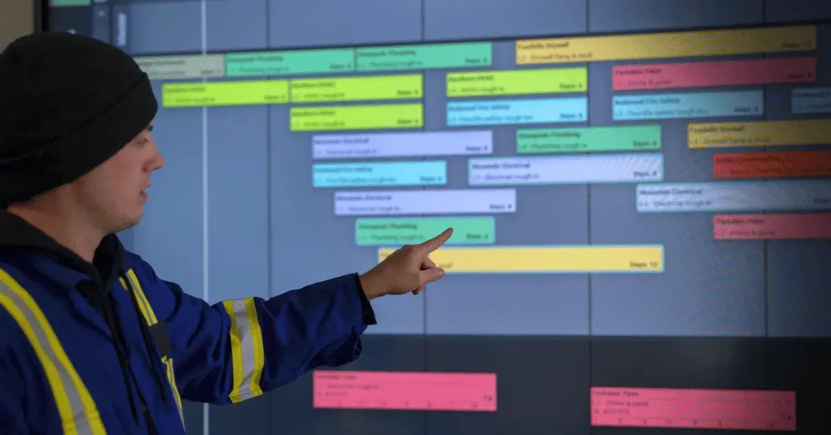 A contractor points towards a digital pull plan on an interactive display.
