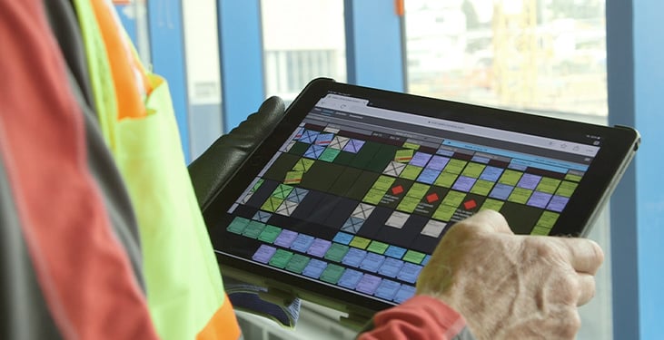 A construction worker checks their weekly work plan on Nialli Visual Planner using an iPad.