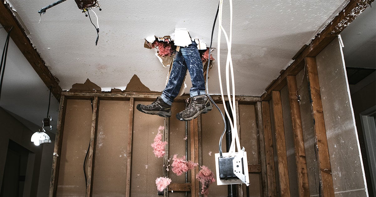 Amusing scene of a man's legs poking through a hole in the ceiling during a DIY project gone wrong.