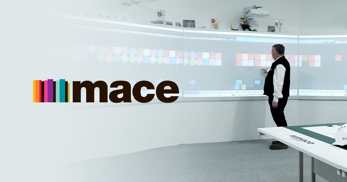 Steve Hawthorne, Director of Operations at Mace, stands in front of a series of interactive displays and moves tasks around in Nialli Visual Planner with his right hand.
