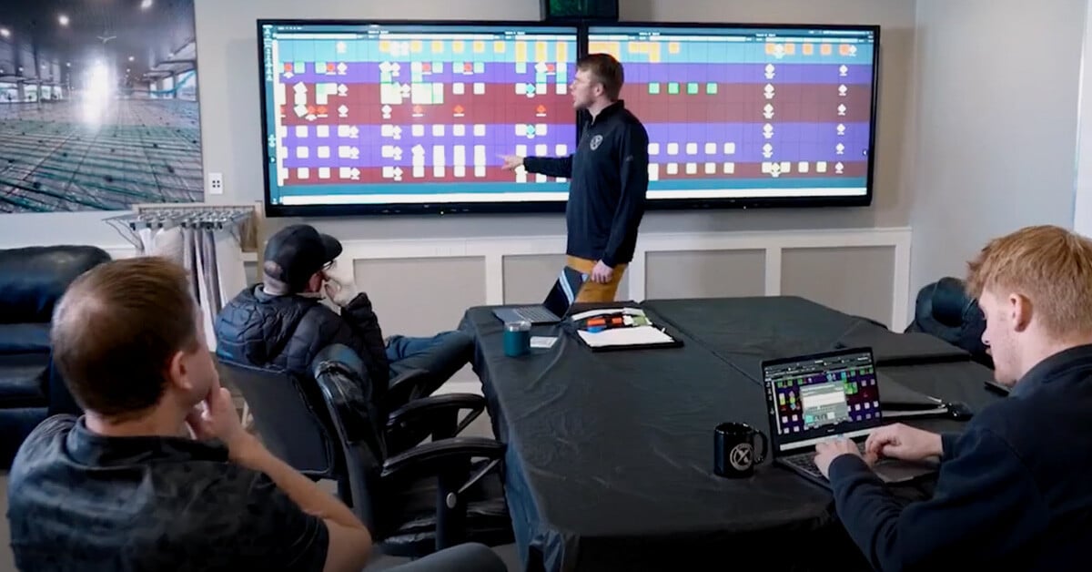 Four members of the Extreme Concrete team using Nialli Visual Planner, which is shown on a double display at the front of the room and on a laptop computer placed on the meeting room table.